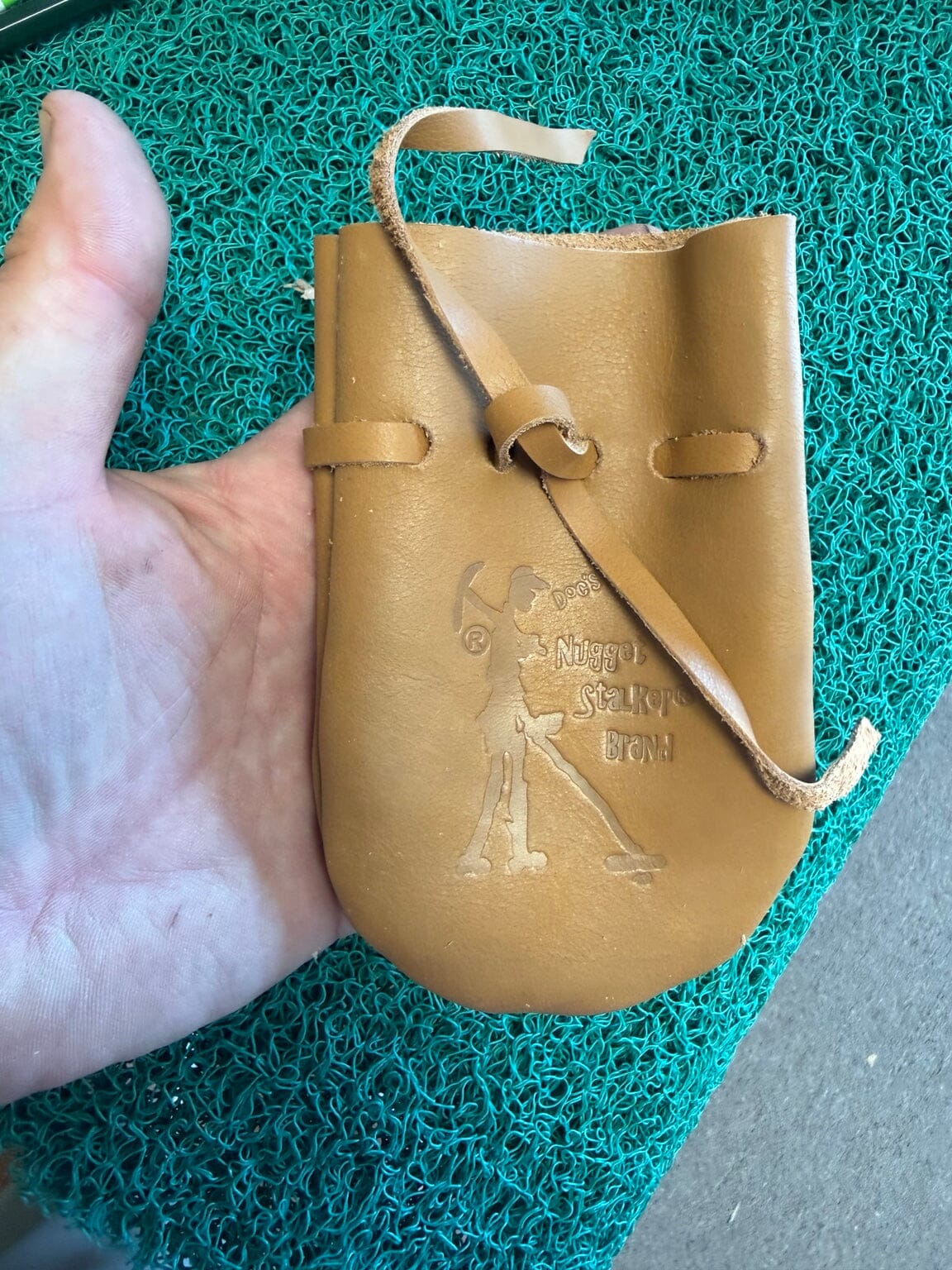 Doc's Nugget Stalker cowhide pouch shown in hand for scale